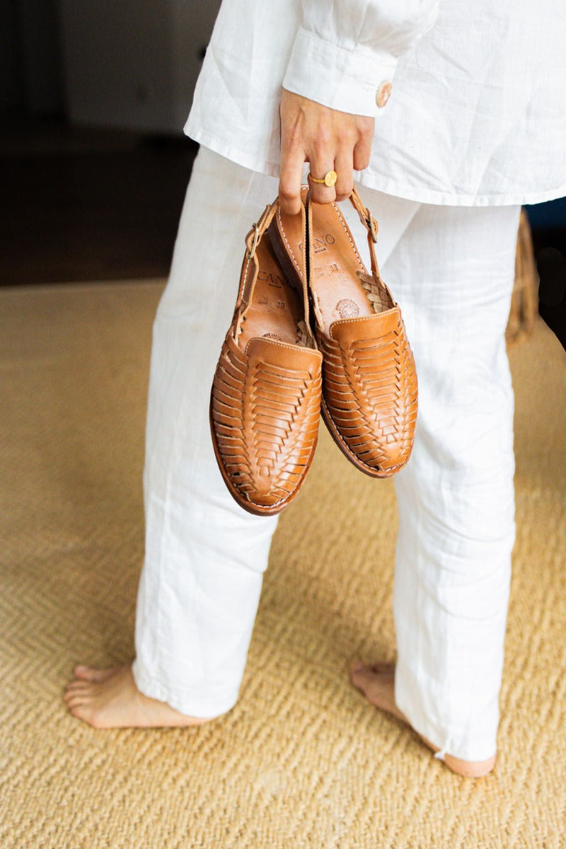 Woman holding handmade sustainable Amelia Sandal in cognac